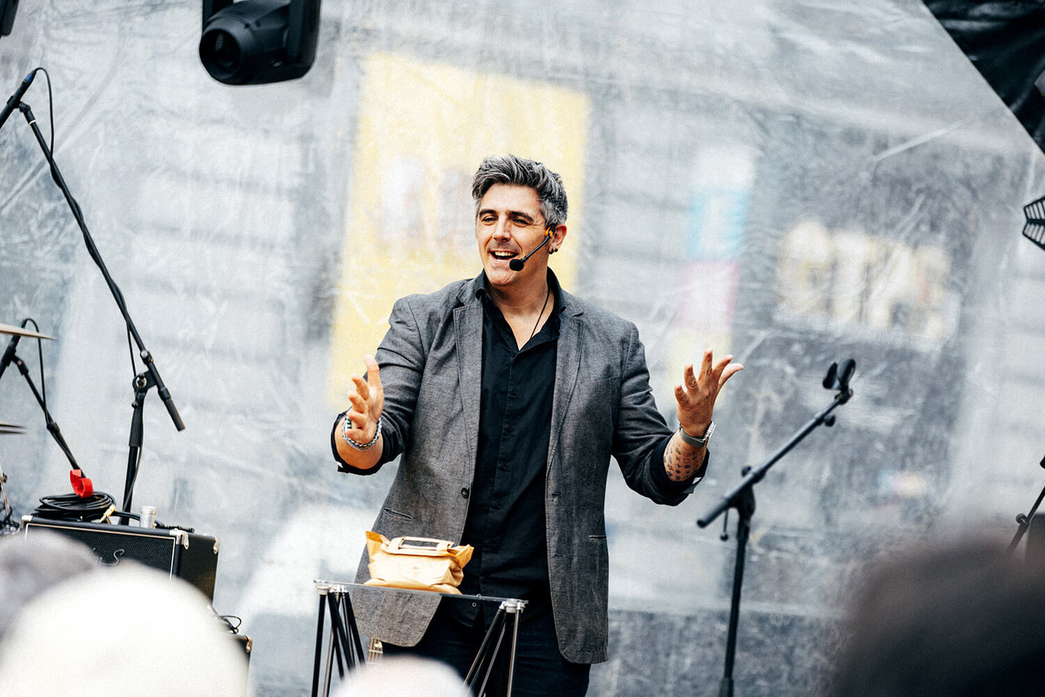 Benjamin Ghislain, mentaliste, interagit avec le public en souriant. Il tient un objet dans sa main gauche, probablement lié à une illusion ou une démonstration de magie cognitive.