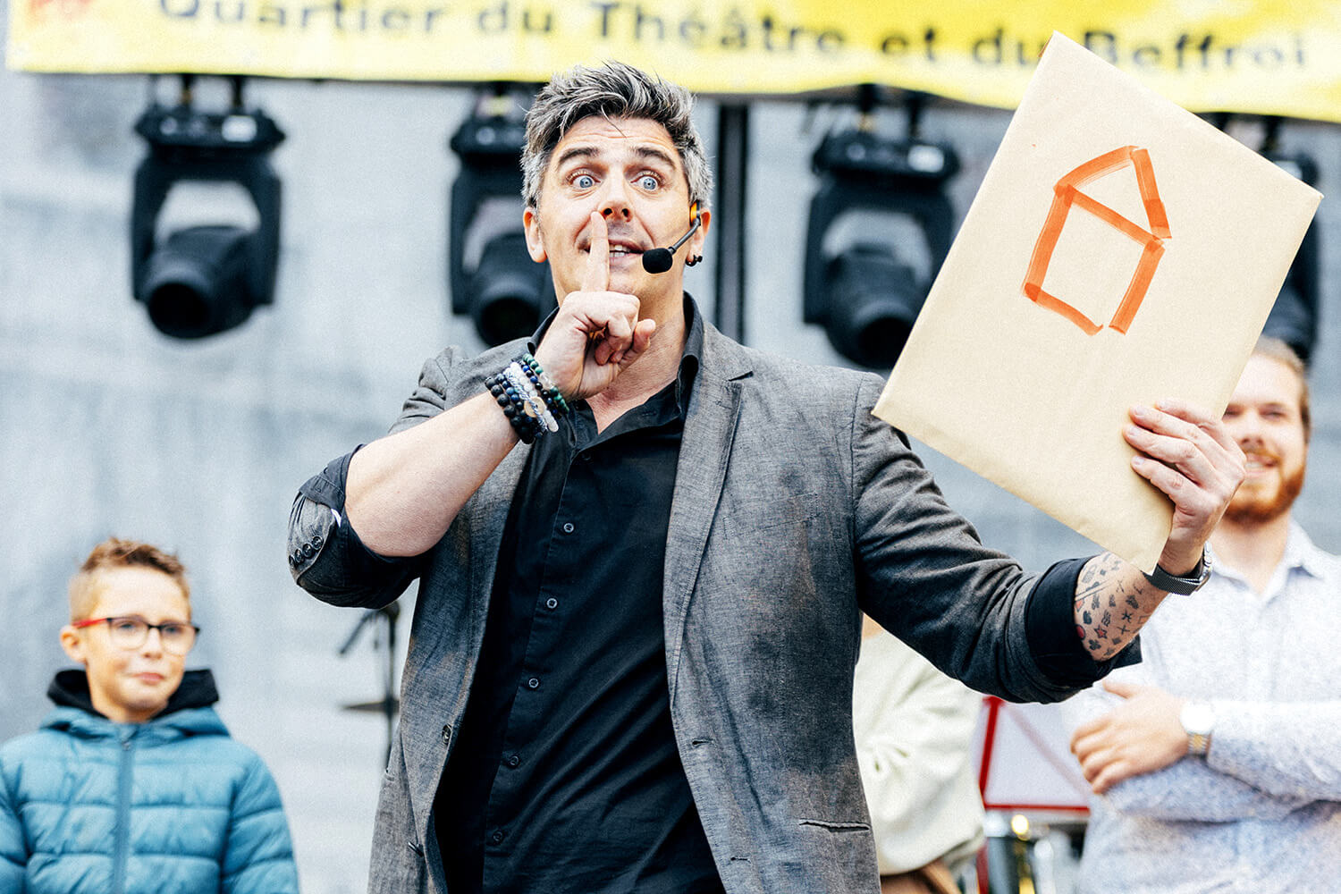 Benjamin Ghislain, mentaliste, montre un dessin de maison réalisé par un spectateur. Il fait un geste de silence pour accentuer le suspense avant de révéler son illusion.