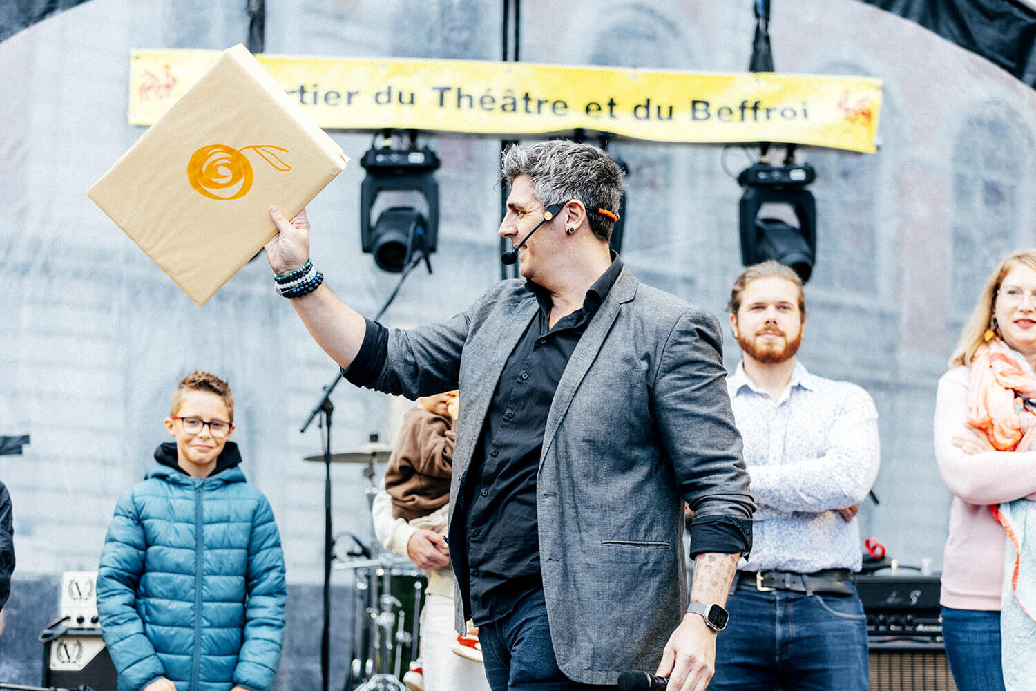 Benjamin Ghislain, mentaliste, révèle un dessin deviné lors de son numéro. Autour de lui, des spectateurs, dont des enfants, tiennent leurs propres dessins, illustrant la participation interactive du public.