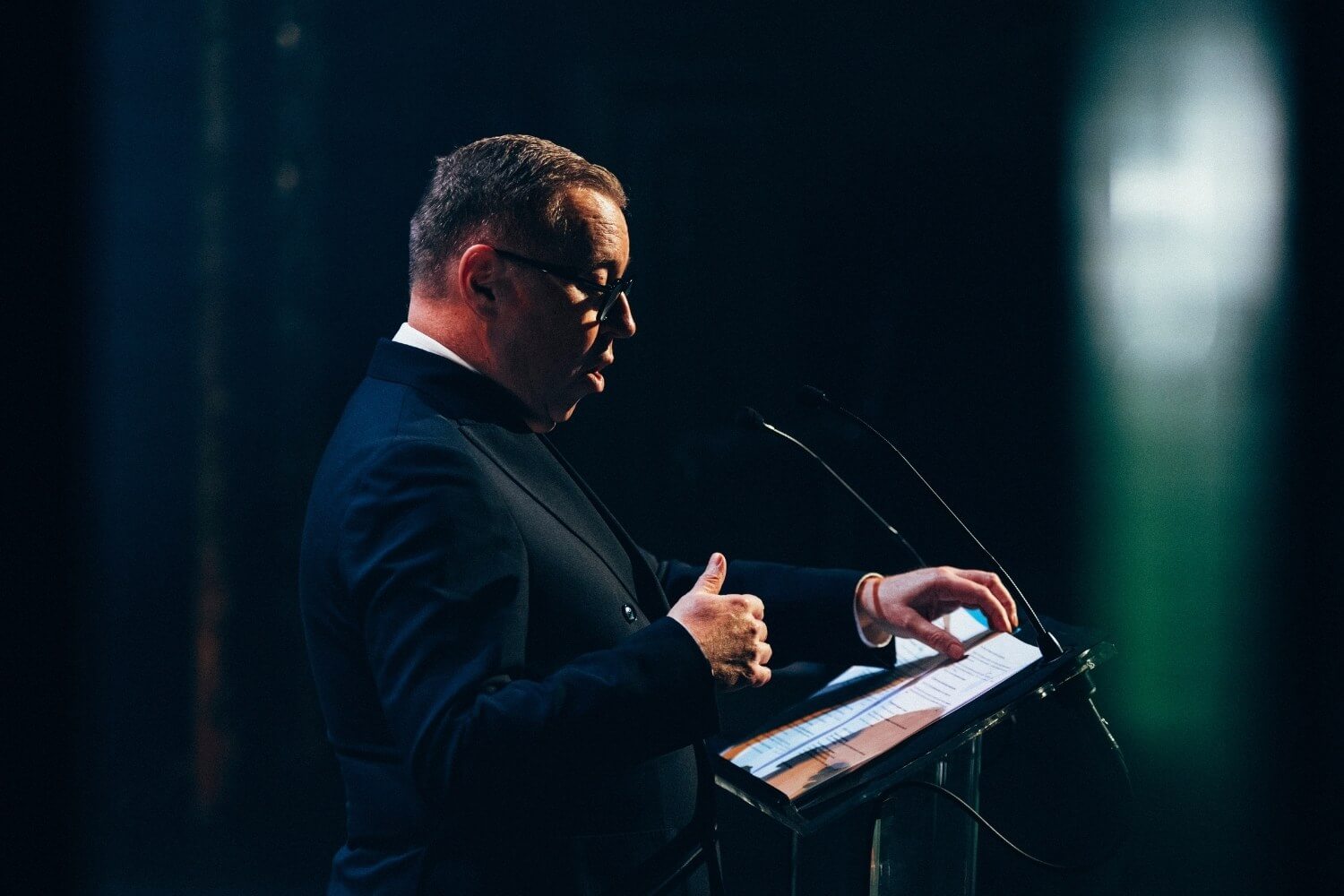 Denis Mathen consulte ses notes sur scène afin de structurer un message appelant à une gouvernance responsable et collective des usages de l’intelligence artificielle.